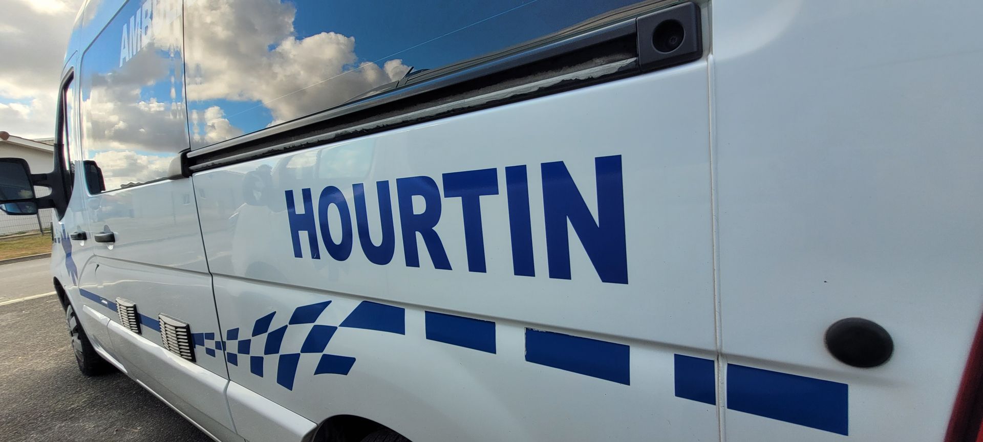 Côté du véhicule avec l'inscription HOURTIN et un autocollant à damier de style police.