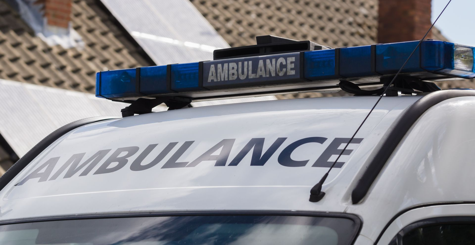 Gros plan sur le toit et la partie supérieure avant de la carrosserie d'une ambulance, avec sa rampe lumineuse d'urgence.
