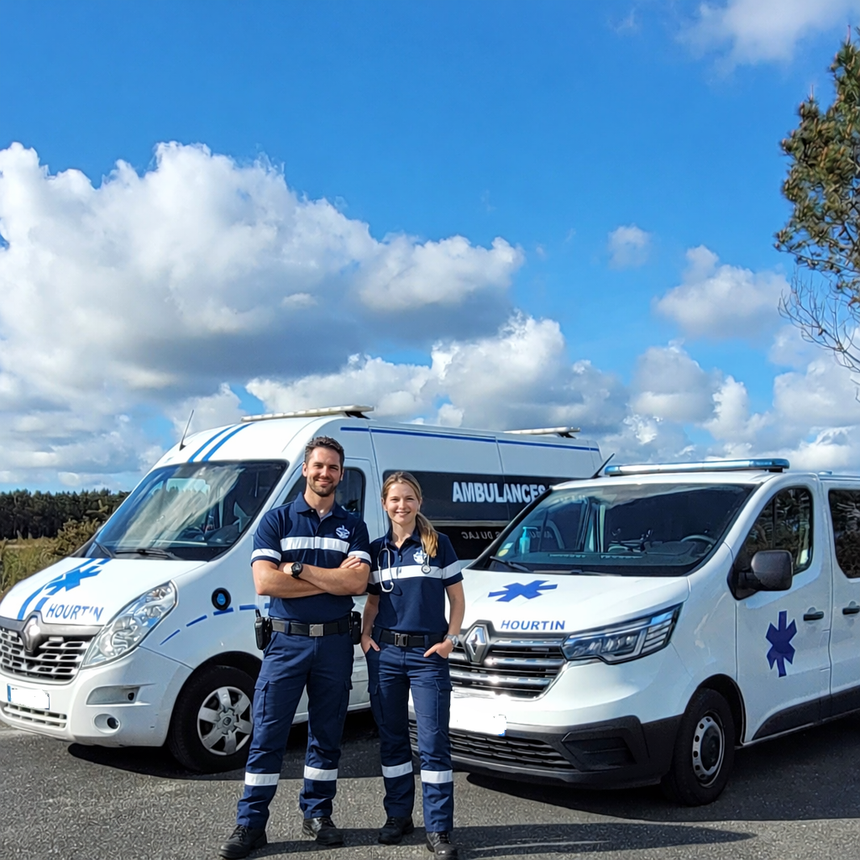 Deux secouristes sourient entre deux ambulances.