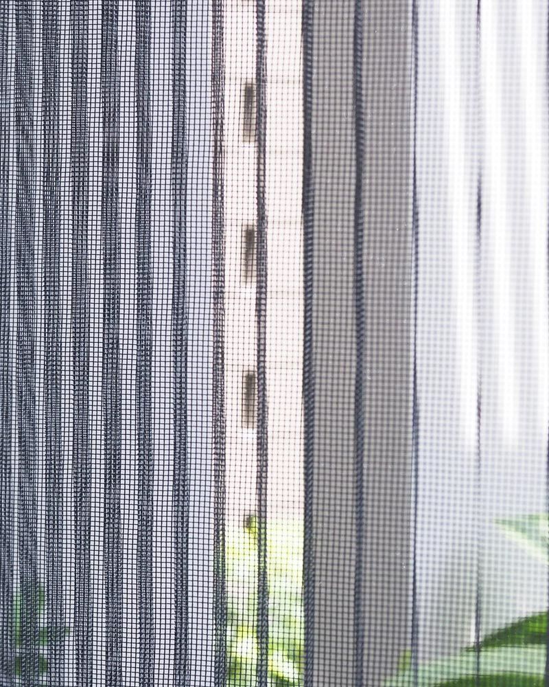 Cortinas transparentes junto a una ventana con luz natural tenue y hojas verdes visibles en el exterior.