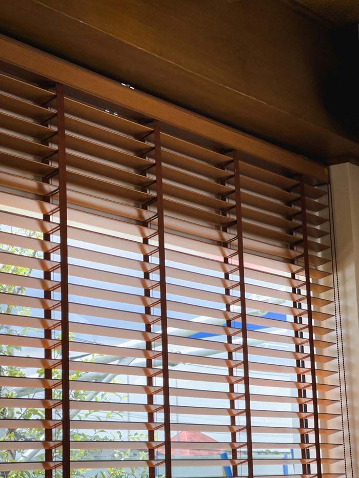 Persianas de madera enmarcando una vista del cielo azul y los tejados del exterior