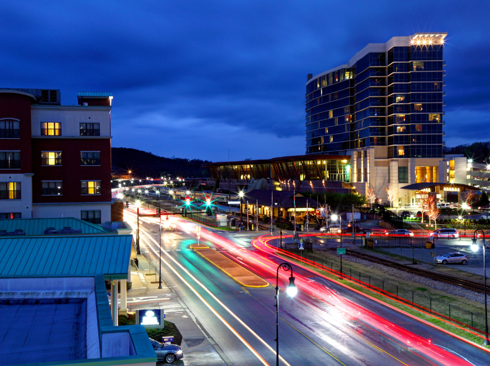 A city street at night with a hotel in the background