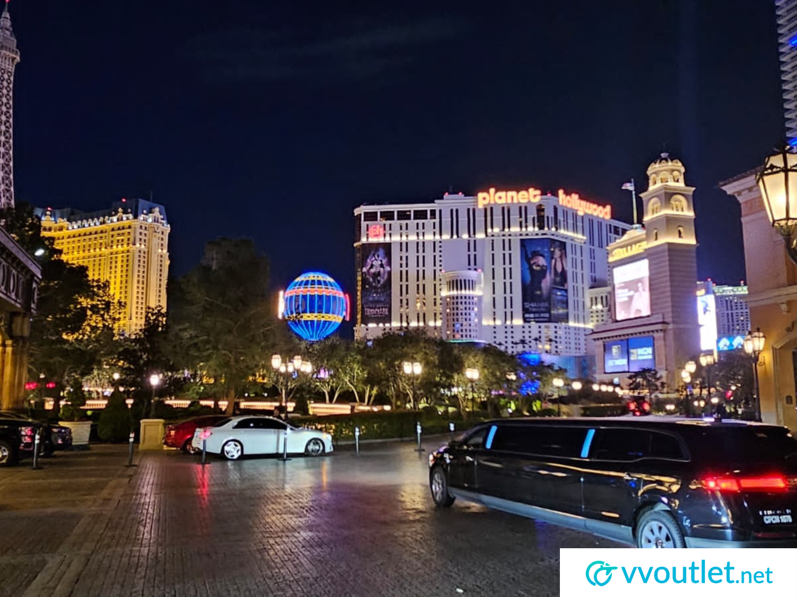 A limousine is parked in front of a casino at night.