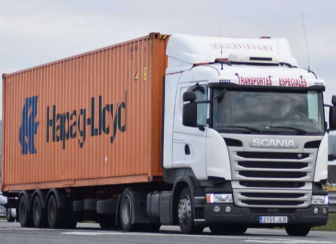Un camión blanco y naranja con la palabra Scania en el frente.