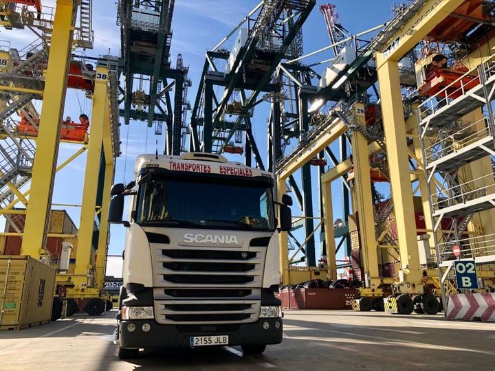 Un camión Scania está estacionado delante de una gran grúa.