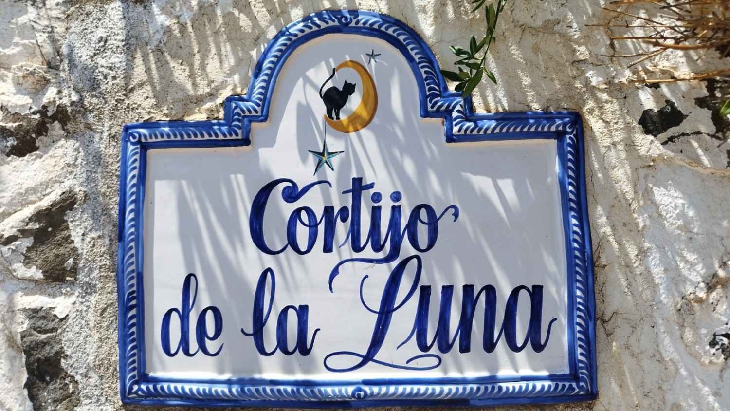 Un letrero de azulejos blancos con el texto cursivo azul 