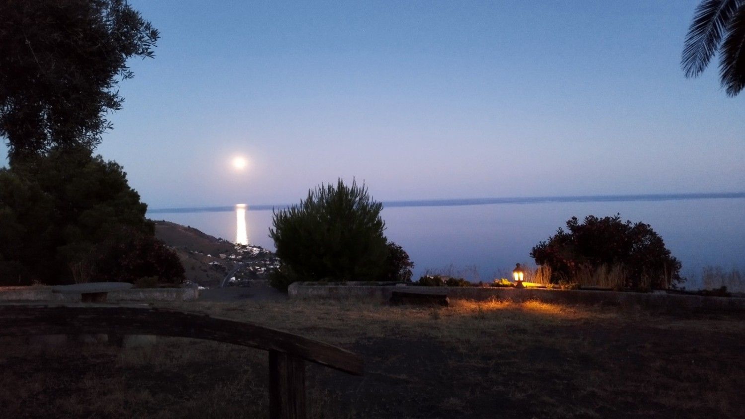 Una luna brillante se eleva sobre un lago en calma al anochecer