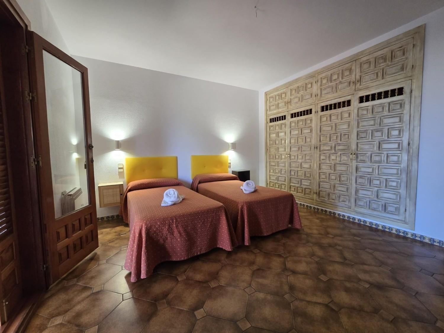 Dos camas individuales con colchas de color naranja rojizo