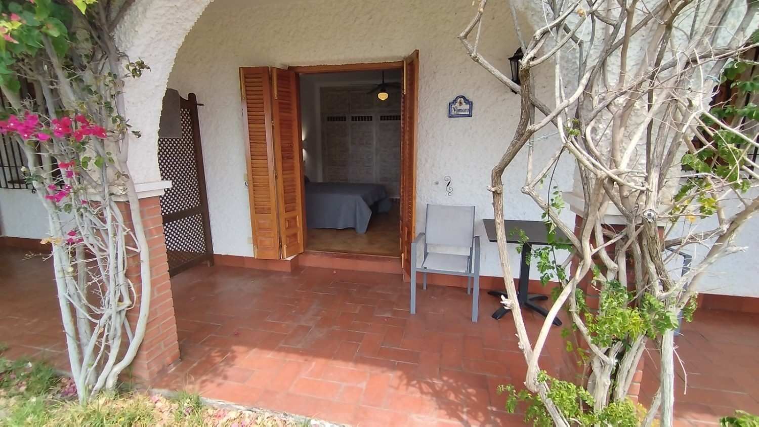 Un patio soleado con suelo de terracota y una entrada arqueada 