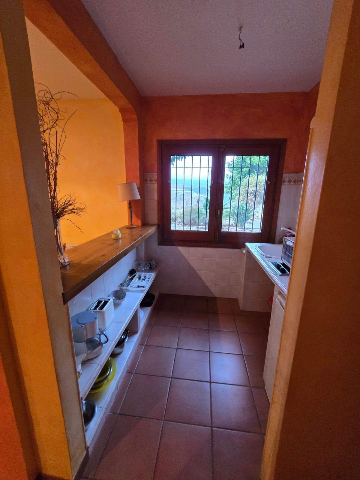 Una cocina tipo galera con suelo de baldosas de terracota, paredes naranjas