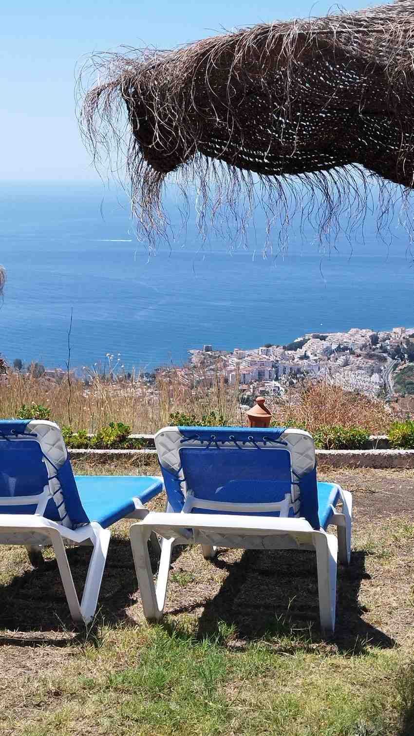 Dos tumbonas azules se encuentran en un mirador cubierto de hierba,