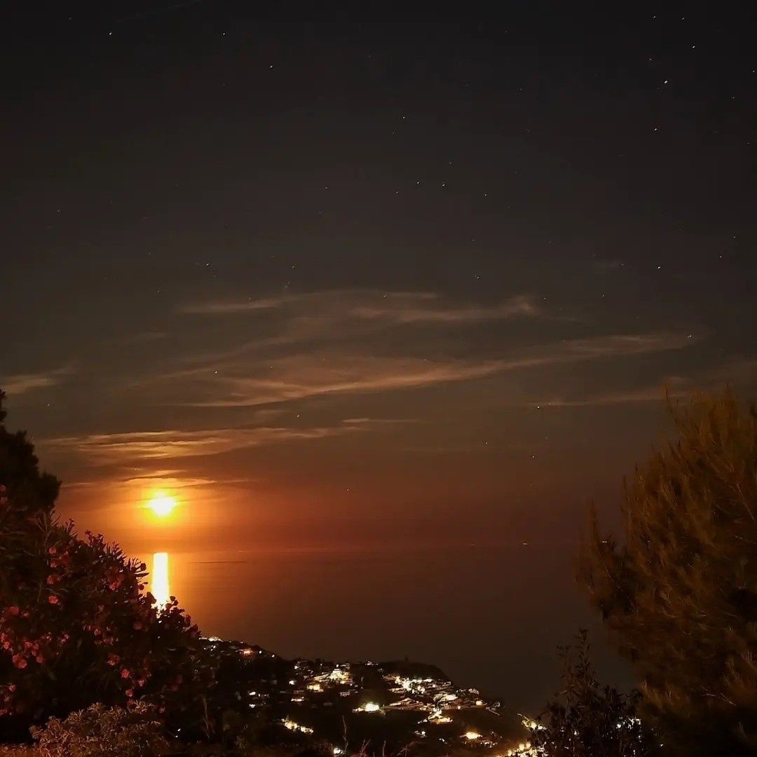 Una luna brillante se eleva sobre un océano oscuro, proyectando un reflejo 