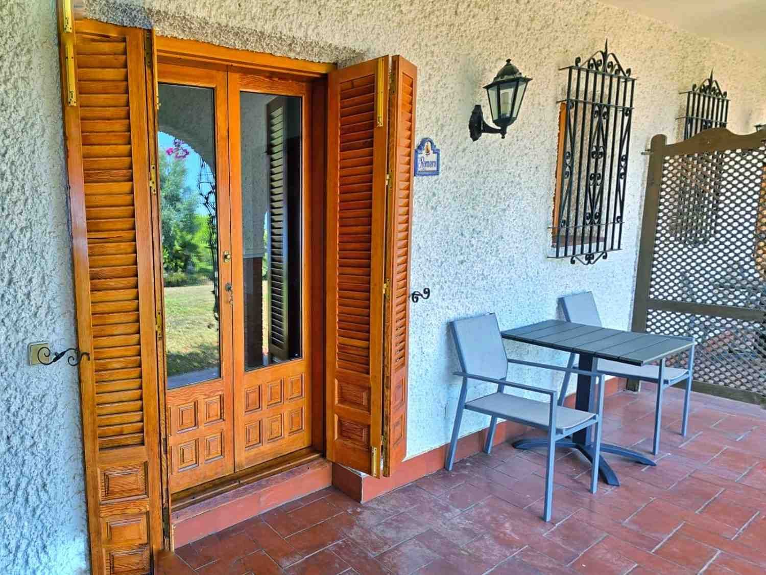 Un patio con puertas de madera con contraventanas abiertas, una mesita