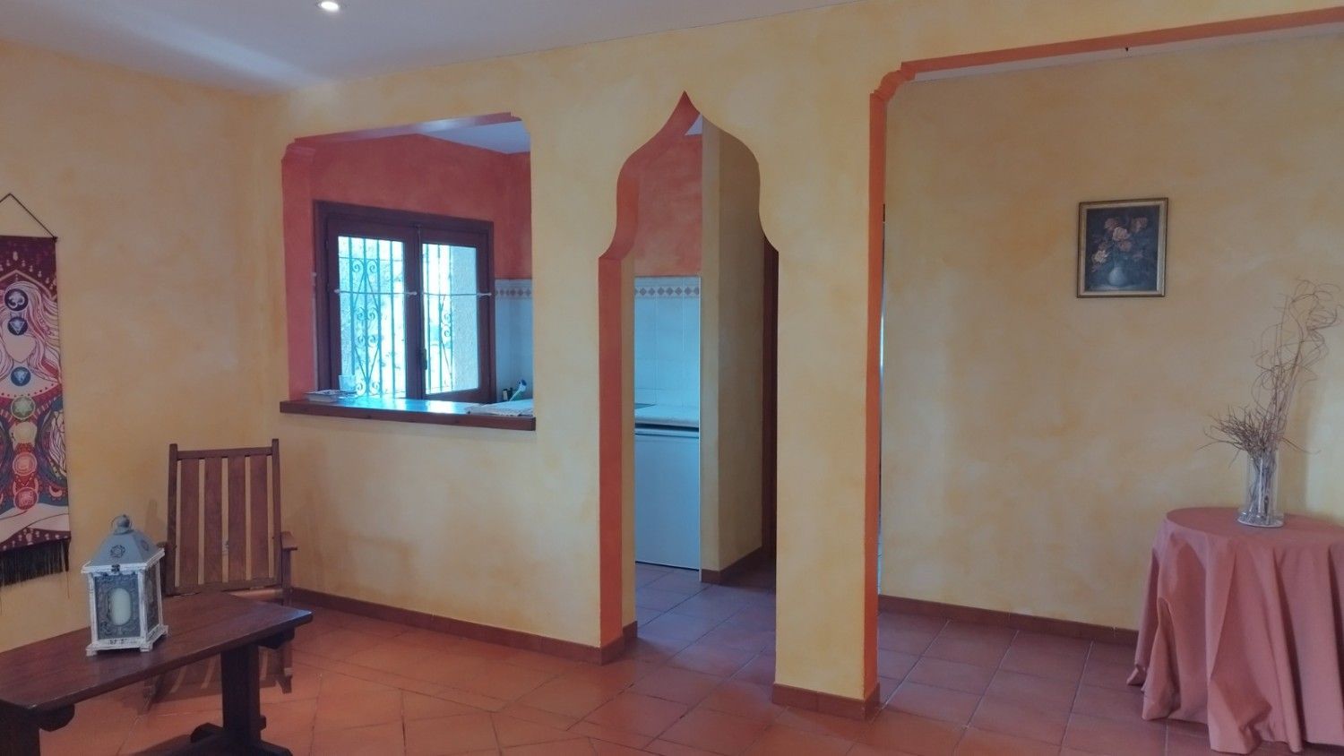 Una habitación amarilla con puertas arqueadas, una silla de madera