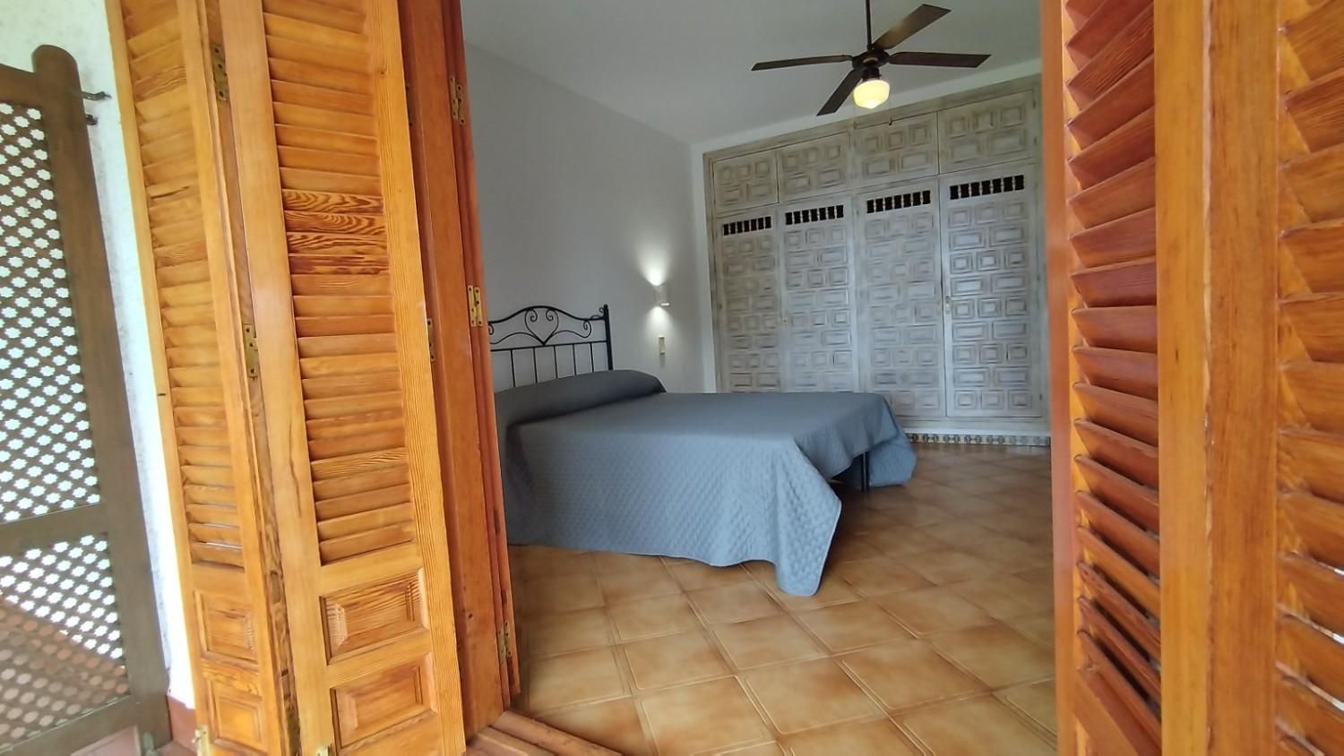 Un dormitorio con una cama con funda gris, estructura oscura