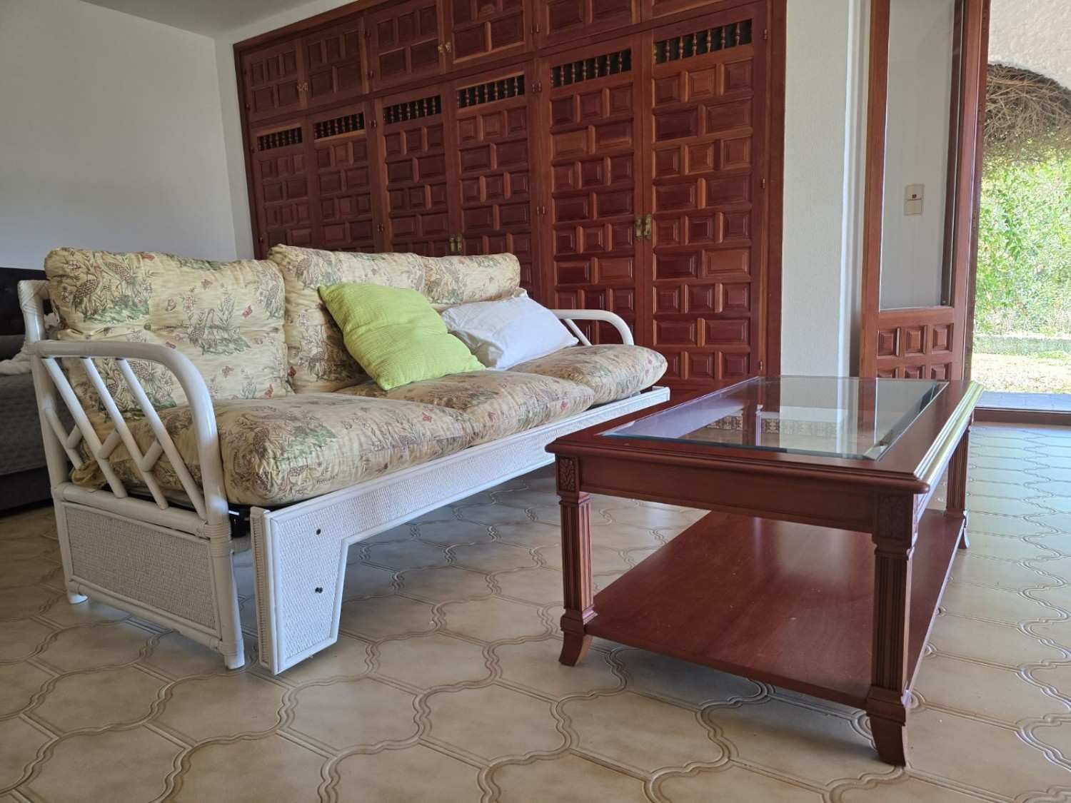 Un futón de mimbre blanco con un cojín 