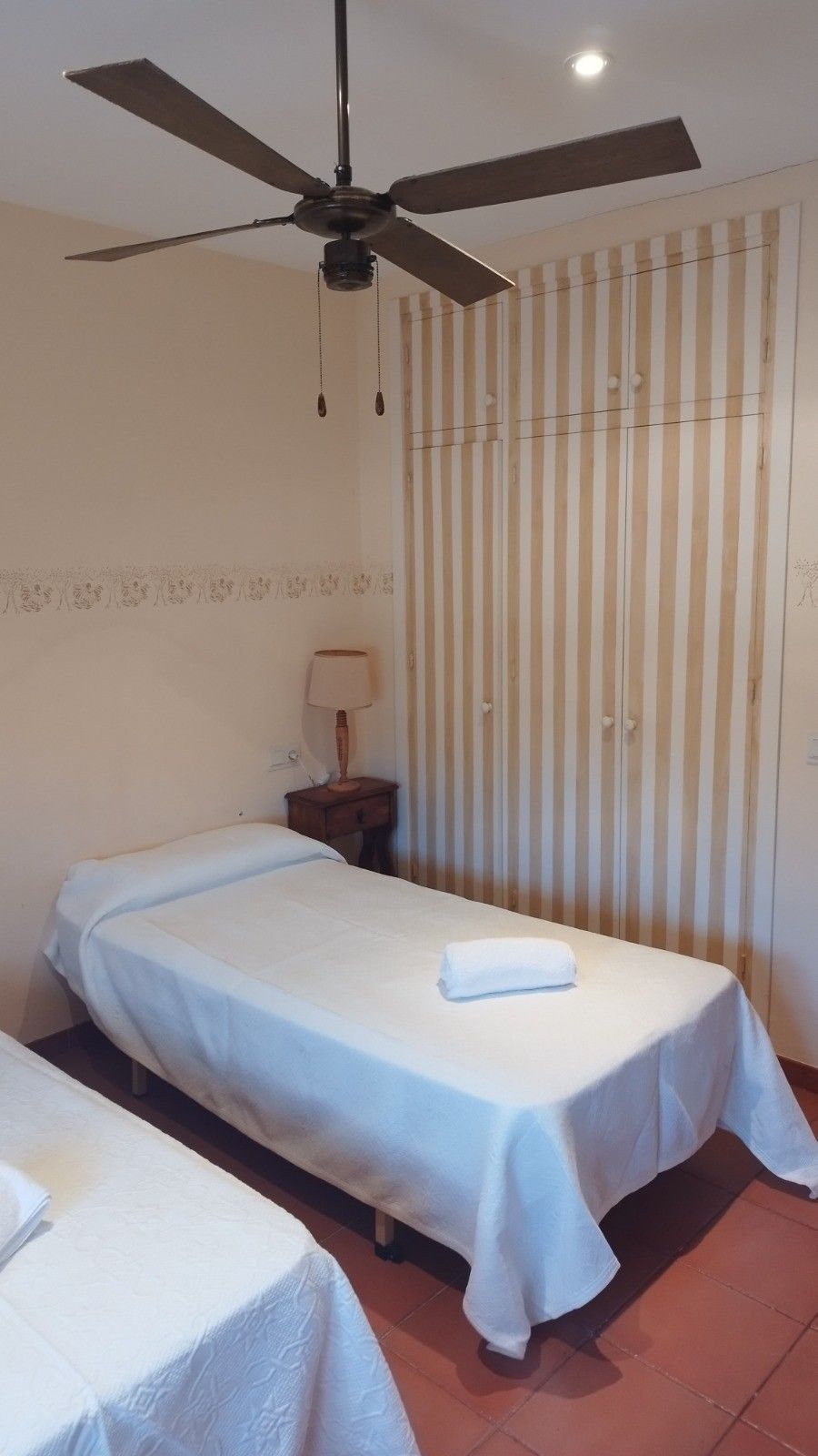 Una habitación de hotel con dos camas individuales, un ventilador de techo