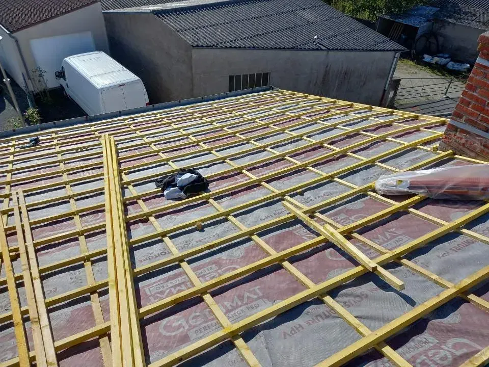 Toiture en construction avec poutres en bois apparentes et isolation.