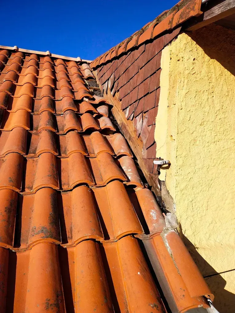 Un toit de tuiles rouges côtoie un mur couvert de bardeaux bruns