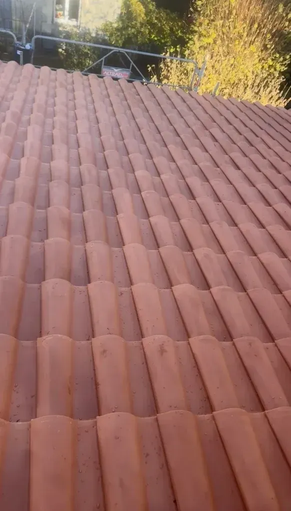 Tuiles de toit en céramique rouge, inclinées, au soleil.