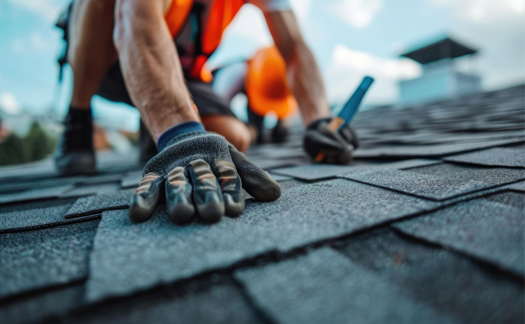 Un couvreur pose des bardeaux d'asphalte sur un toit, portant des gants et un équipement de sécurité.