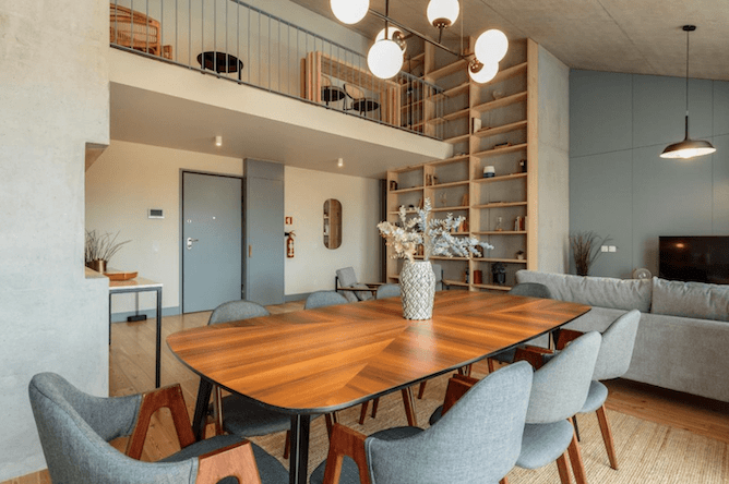 Dining area with wooden table and chairs, built-in bookshelves, and mezzanine level.