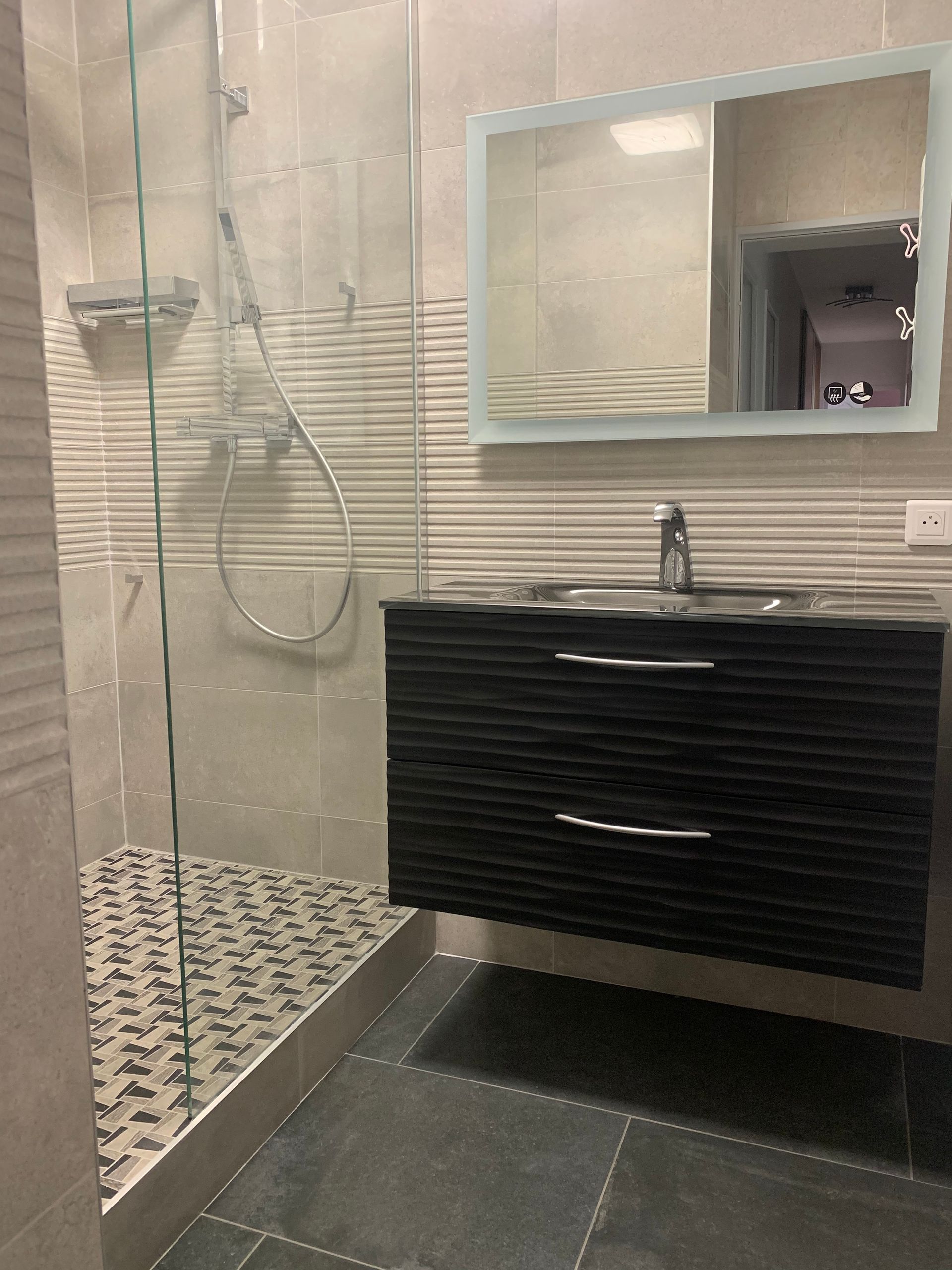 Vasque noire sous un miroir et à côté d'une douchr