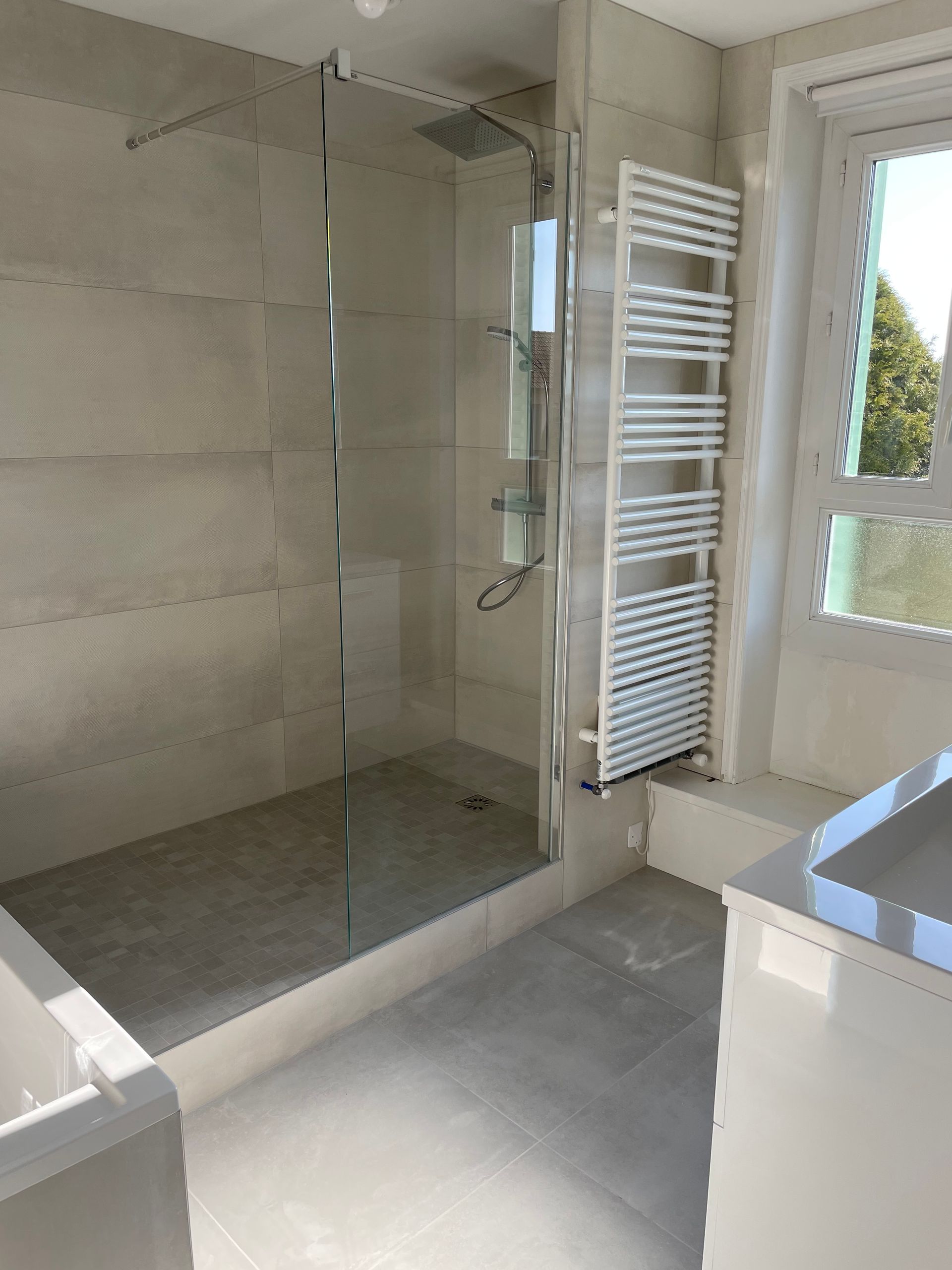 Douche à l'italienne grise avec un sèche-serviette