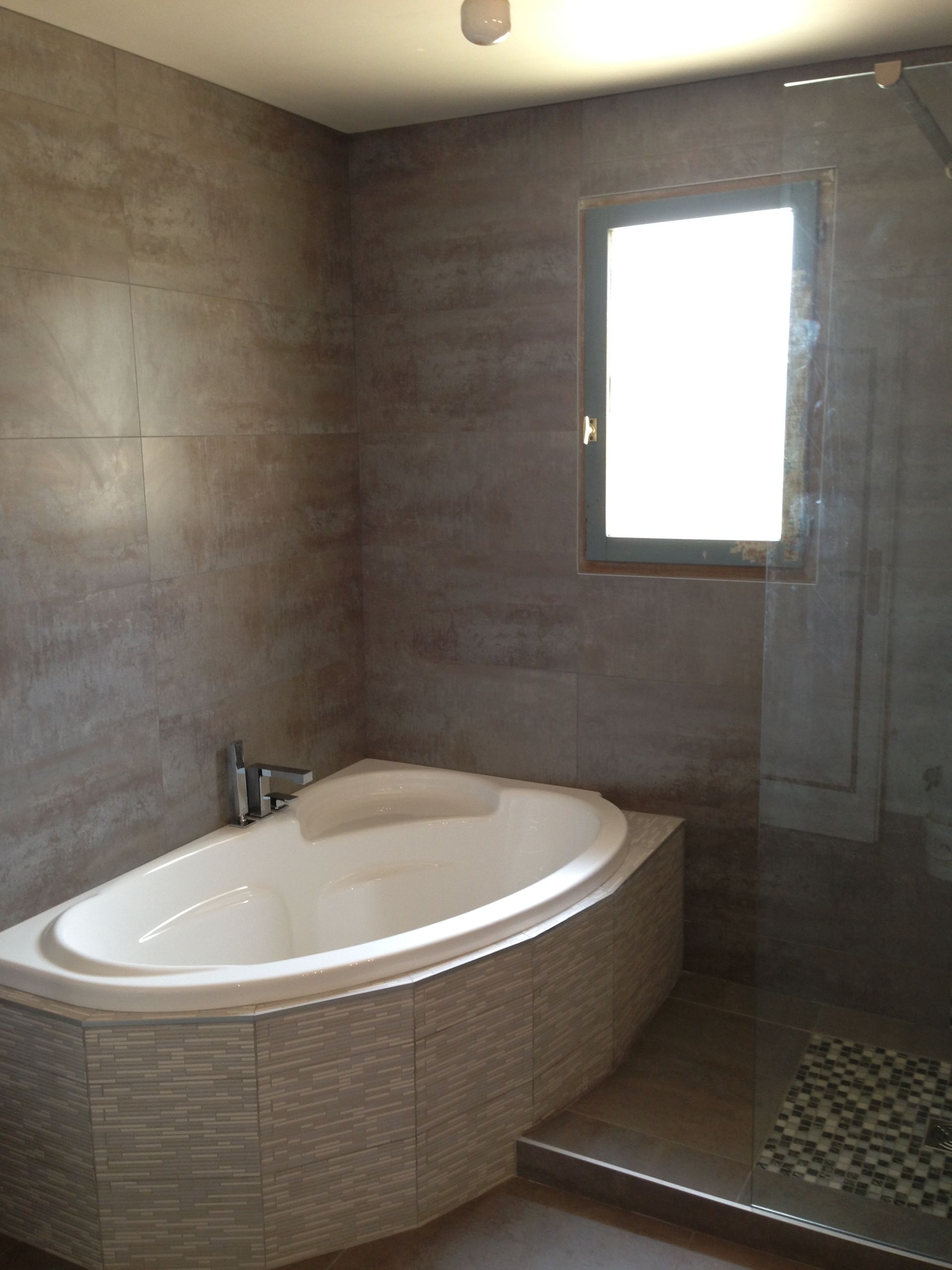 Baignoire d'angle juste à côté d'une fenêtre et d'une douche à l'italienne