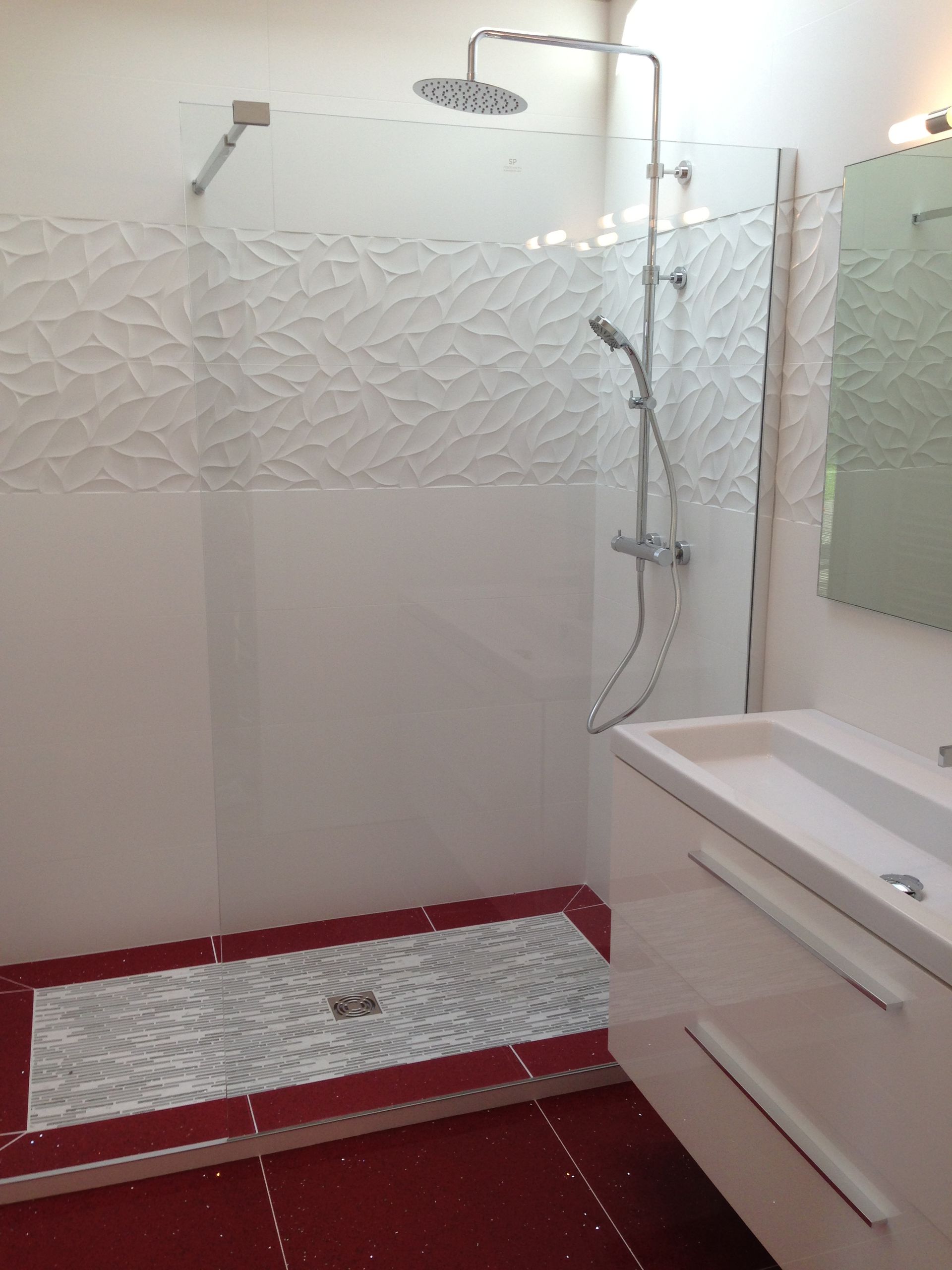 Salle de bain entièrement blanche, à l'exception du sol rouge de la douche