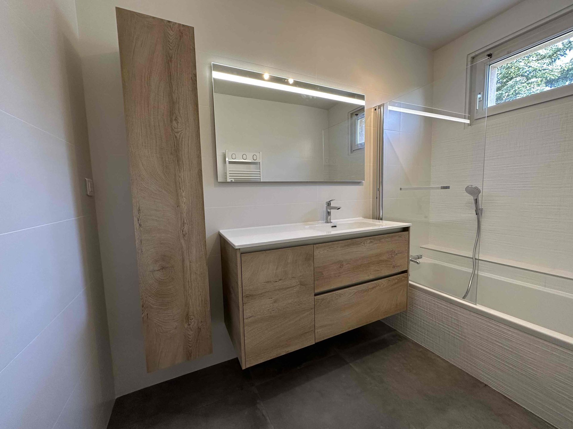 Meubles de salle de bains imitation bois, à côté d'une baignoire