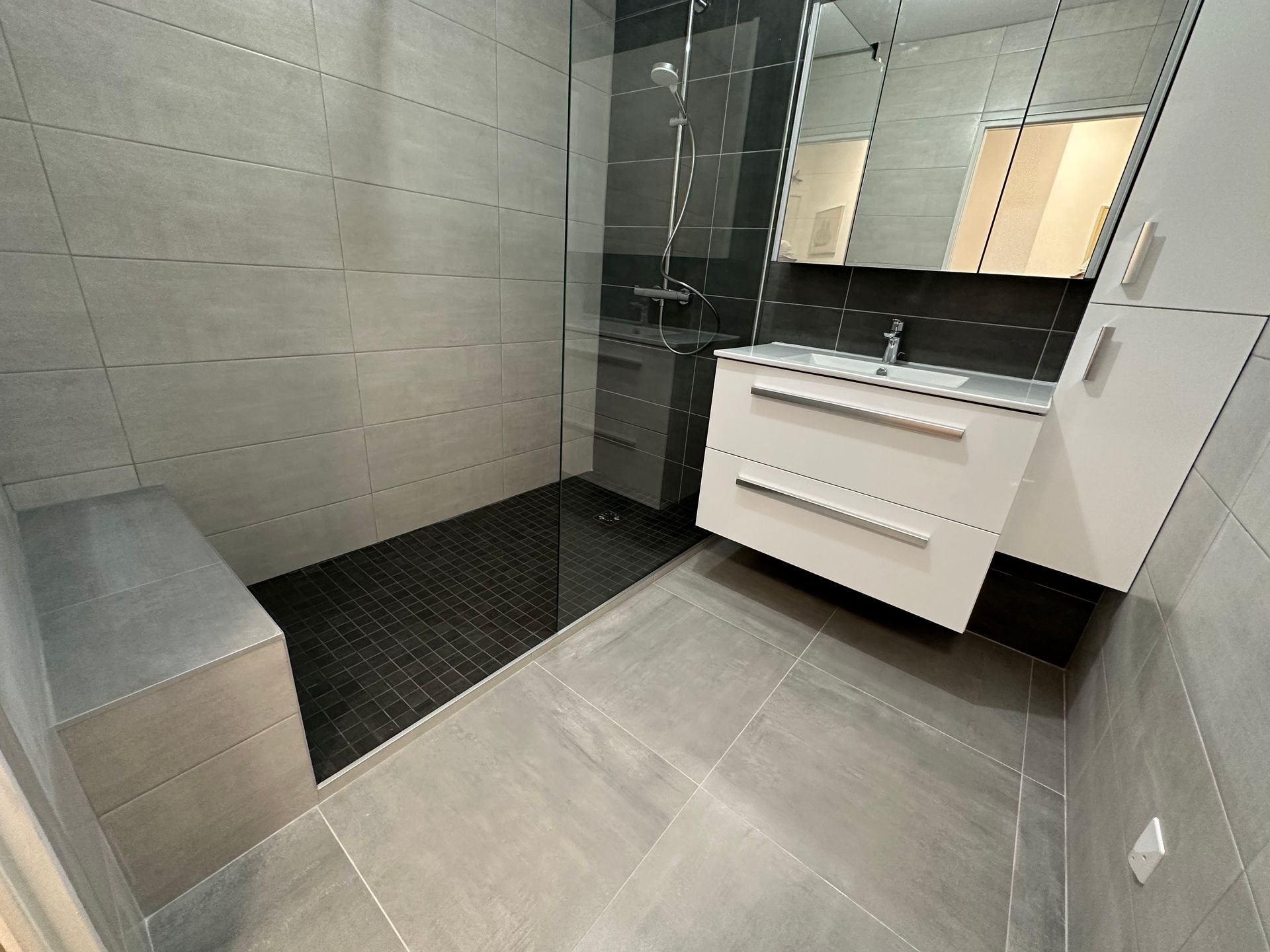 Salle de bains blanche et grise avec une douche à l'italienne noire