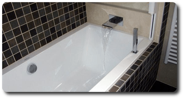 Baignoire à petits carreaux noirs et robinet en cascade