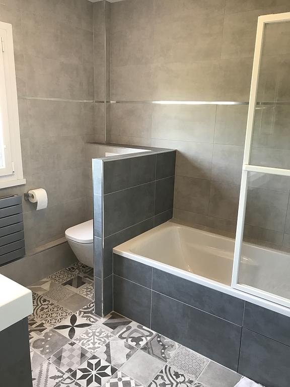 Espace baignoire et toilettes avec un carrelage gris
