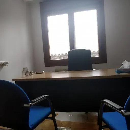 Dos sillas azules están sentadas frente a un escritorio en una oficina.