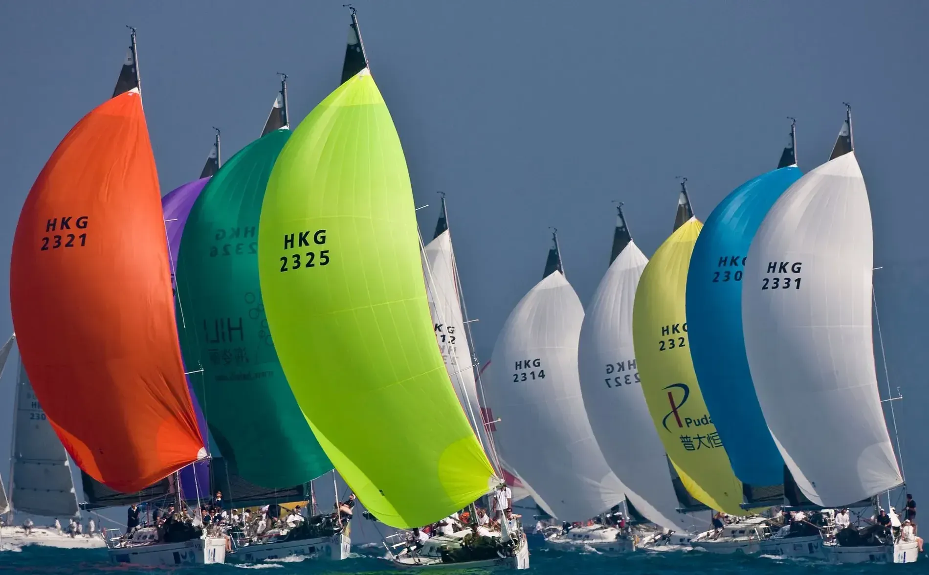 Velero escorándose en un océano agitado, tripulación en cubierta, rocío levantándose, velas llenas.