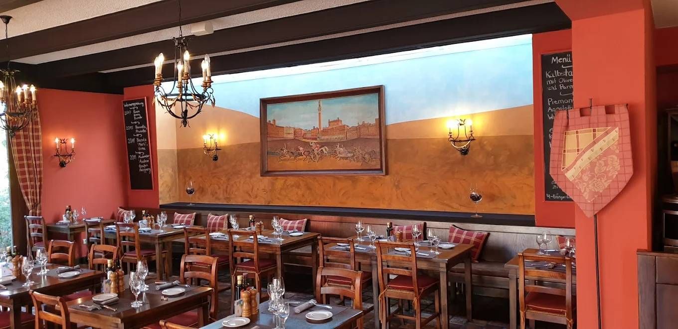 Restaurantinterieur mit gedeckten Tischen, roten Wänden und einem Gemälde an der Wand.