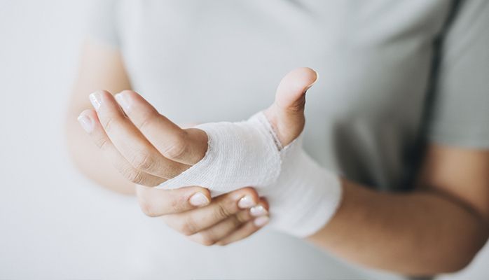 Une femme enveloppe sa main dans un bandage.