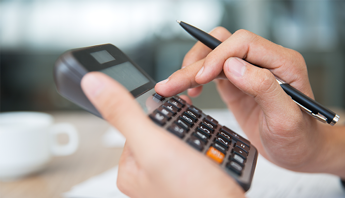 Une personne utilise une calculatrice et tient un stylo.