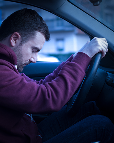 Un homme est assis dans une voiture avec sa tête sur le volant.