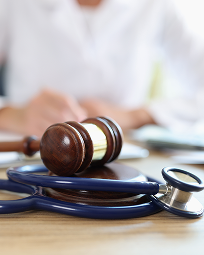 Un marteau de juge et un stéthoscope sont sur une table en bois.