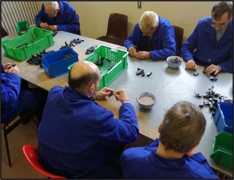 Un grupo de hombres están sentados alrededor de una mesa trabajando en un proyecto.