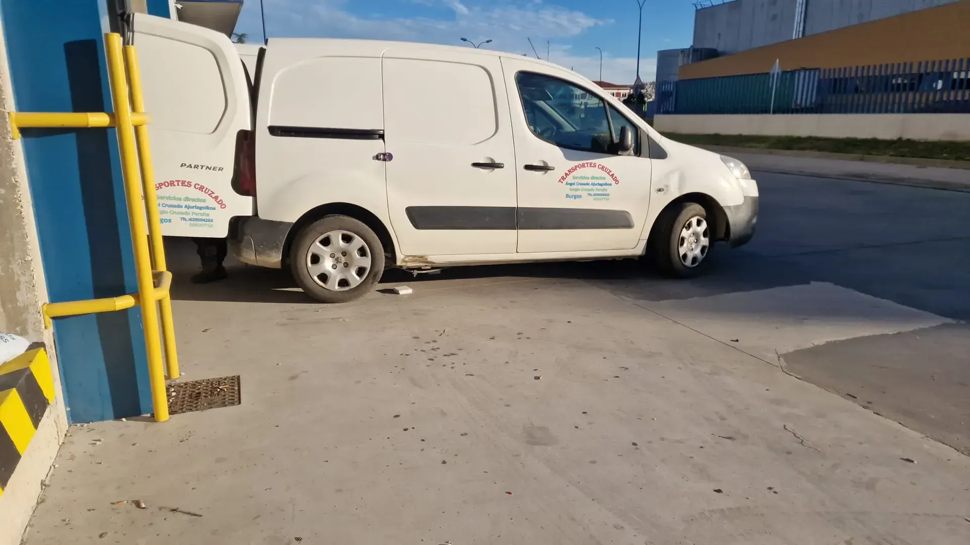 Camión semirremolque rojo circulando por una autopista debajo de un paso elevado de hormigón.