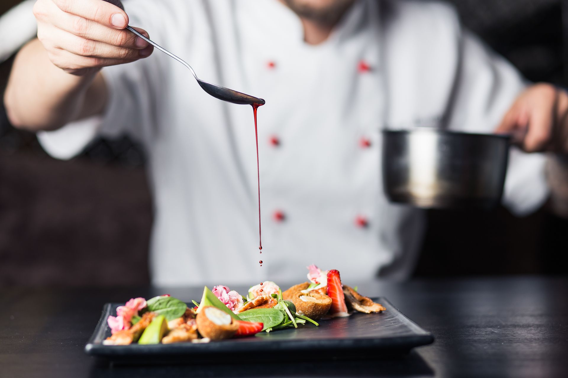 Chef cuisinier qui verse un coulis dans son plat