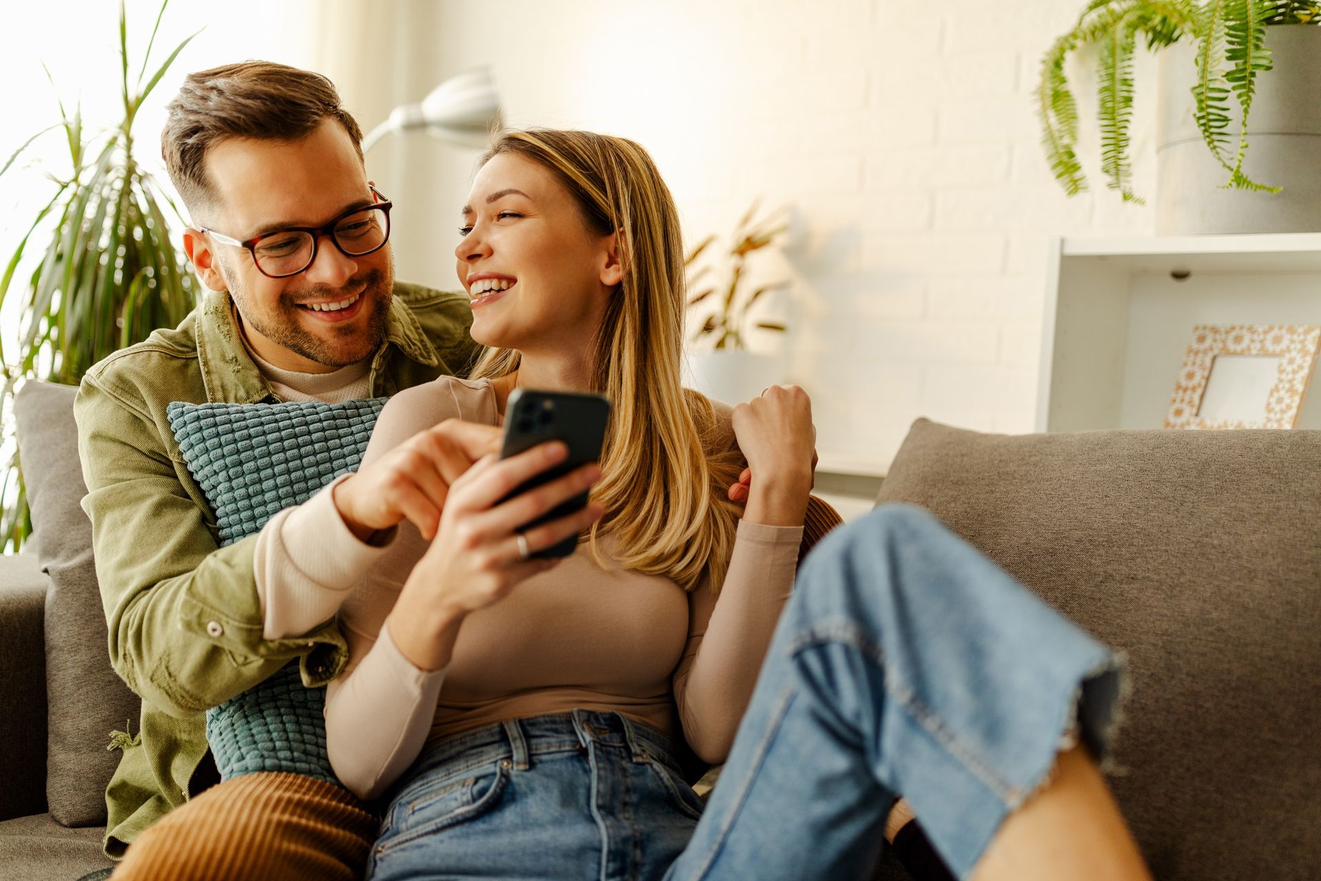 Un jeune couple ravi célèbre le triomphe après avoir lu une bonne nouvelle inattendue sur son smartphone.