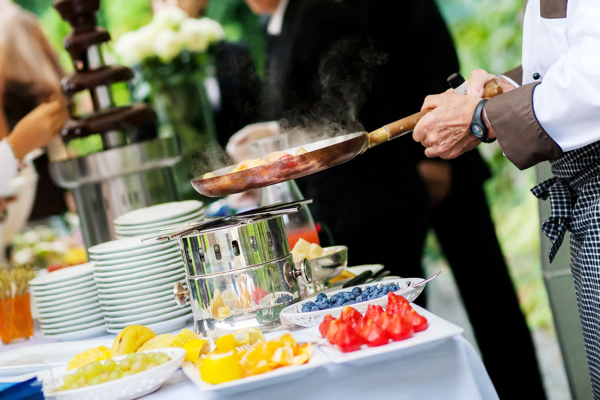 Chef qui fait chauffer des ingrédients dans une poêle durant un buffet