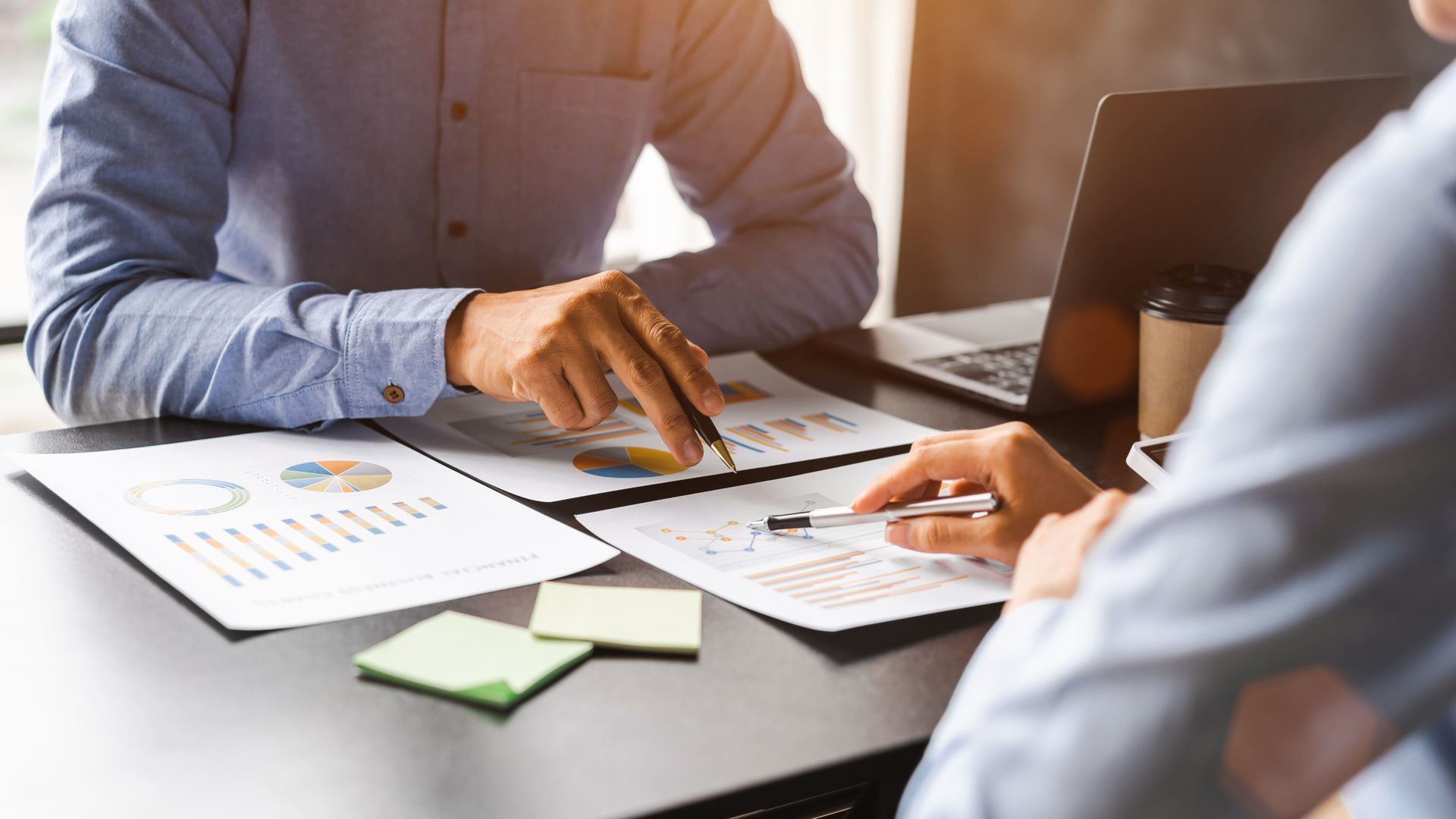 Des personnes consultent des graphiques et des tableaux imprimés à un bureau.