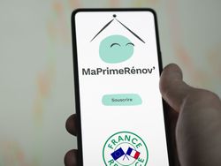 Une main tenant un téléphone avec le logo de MaPrimeRénov.