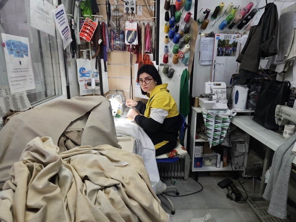 Una mujer está usando una máquina de coser para coser un trozo de tela.