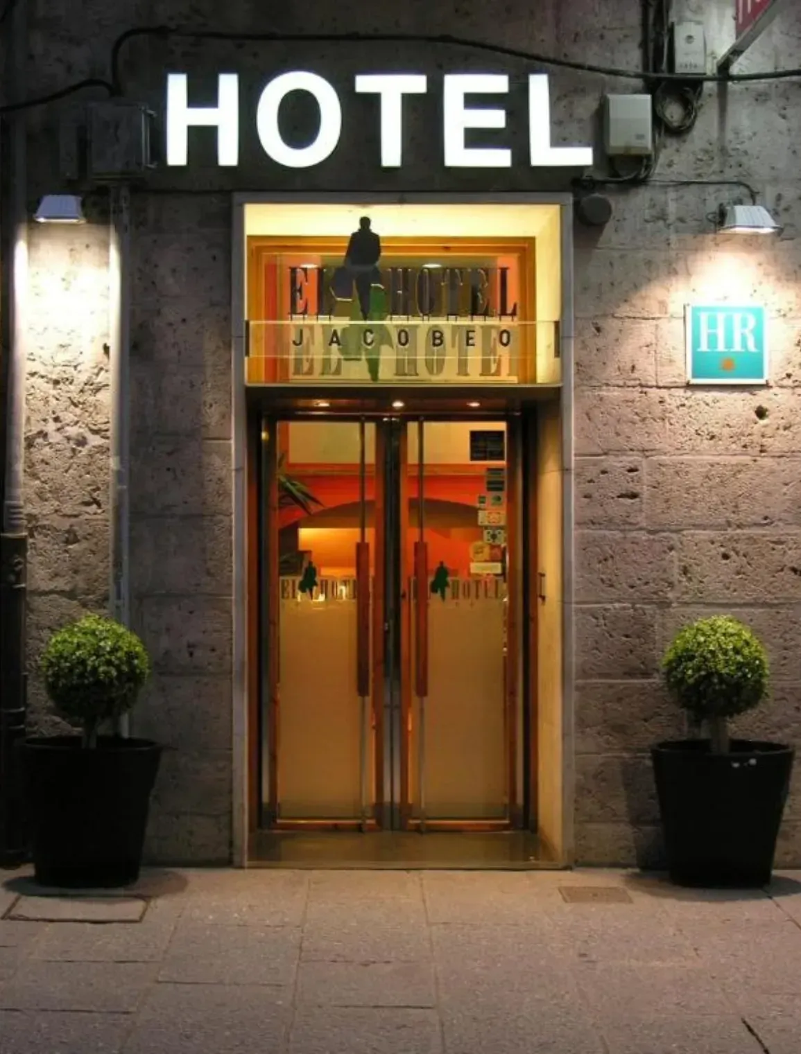 Entrada del hotel de noche, con cartel iluminado de 